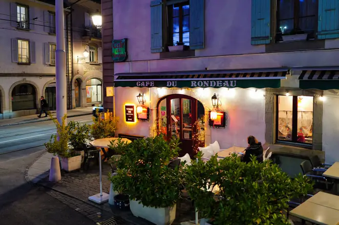 Façade du Café du Rondeau éclairée le soir, à Carouge